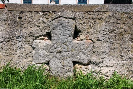Wągrodno, pow. legnicki, gm. Ruja; piaskowcowy krzyż wmurowany w ogrodzenie cmentarza kościelnego, słabo widoczny ryt kuszy