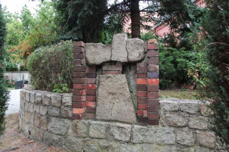 Lubsko, pow. żarski. Fragmenty krzyża wstawione w murek otaczający cmentarz kościoła Najświętszego Serca Pana Jezusa. Pierwotnie krzyż stał w Strzegowie w pow. krośnieńskim. Być może to krzyż nagrobny francuskiego oficera lub trzech oficerów armii napoleońskiej zastrzelonych w 1813 r.