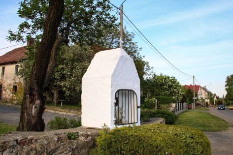 Męcinka, pow. jaworski; głowica kamiennej kapliczki w ogrodzeniu